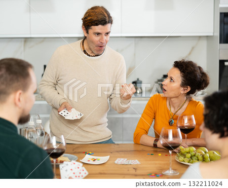 Happy group of friends playing poker cards and drinking wine Happy group of friends playing poker cards and drinking wine 132211024