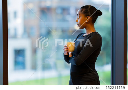 Woman holding coffee near a window Woman holding coffee near a window 132211139
