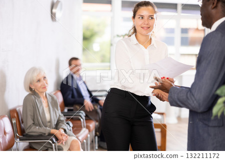 Woman makes deal, shaking hands with middle-aged African man colleague while standing in office Woman makes deal, shaking hands with middle-aged African man colleague while standing in office 132211172