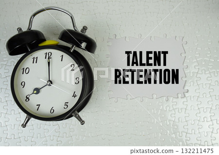 Jigsaw puzzle with a missing piece with "Talent Retention" and alarm clock on white background 132211475