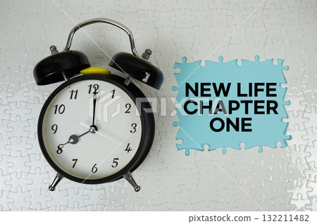Jigsaw puzzle with a missing piece with "New Life Chapter One" and alarm clock on blue background 132211482