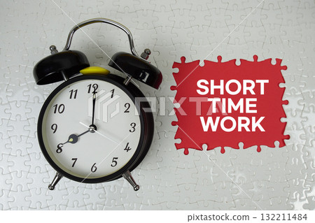 Jigsaw puzzle with a missing piece with "Short Time Work" and alarm clock on red background 132211484