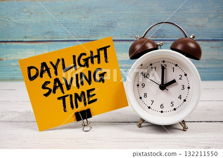 Daylight Saving Time text written on paper card with alarm clock on wooden background Daylight Saving Time text written on paper card with alarm clock on wooden background 132211550