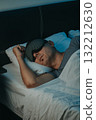 a man lying on his side with a sleep mask in bed 132212630