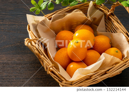 Fresh kumquats in a basket and wood grain background 132214144