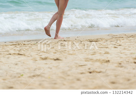 Cheerful asian woman barefoot walking on tropical summer beach. Woman walking along wave of sea water and sand on the beach. Enjoyment barefoot walk outdoor with freedom. Relaxation Travel Concept. 132214342