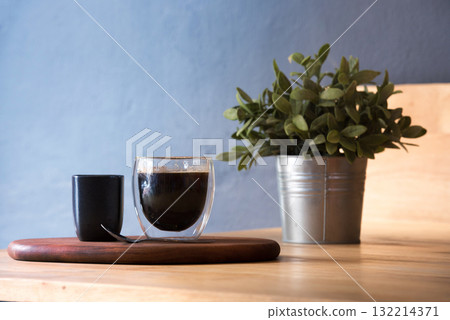 Hot black coffee cup on Wood office desk plant pot decor table blue background. Cup of Black Tea Green potted plant on office wooden desk springtime garden. freshness Home workplace decorate table 132214371