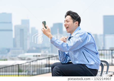 Man in work clothes, smartphone, laughing 132214907