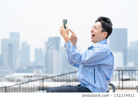 Man in work clothes, smartphone, laughing 132214911