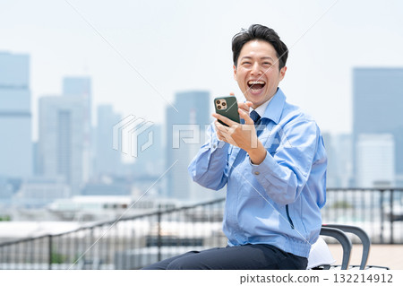 Man in work clothes, smartphone, laughing 132214912