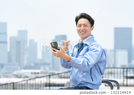 Man in work clothes, smartphone, laughing Man in work clothes, smartphone, laughing 132214914