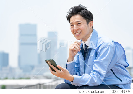 Man in work clothes, smartphone, laughing 132214929