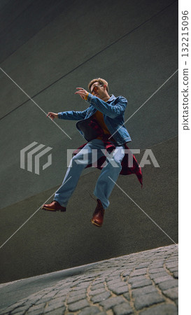 Man jumping in denim jacket and boots between tall stone walls Man jumping in denim jacket and boots between tall stone walls 132215096