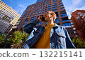 Young man in denim jacket smiling talking on smartphone among modern buildings 132215141