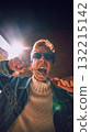 Stylish man biting silver chain under sunlight in expressive streetwear look 132215142