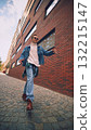 Smiling man in jeans and sunglasses walking through modern city street 132215147