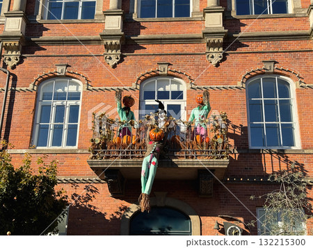 Red Brick House Balcony Decorated with Pumpkins and Scarecrows for Halloween 132215300