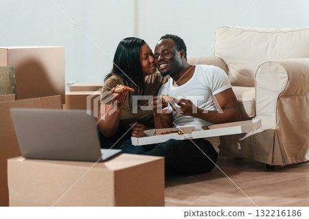 Delicious pizza, sitting by the laptop. African American couple are moving into new house 132216186