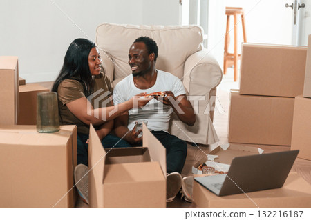 Delicious pizza, sitting by the laptop. African American couple are moving into new house 132216187