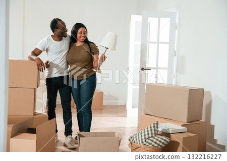 Woman is holding lamp. African American couple are moving into new house Woman is holding lamp. African American couple are moving into new house 132216227