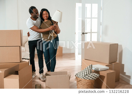 Woman is holding lamp. African American couple are moving into new house 132216228
