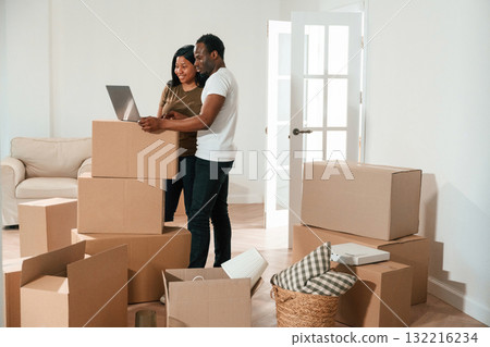 With laptop. African American couple are moving into new house With laptop. African American couple are moving into new house 132216234