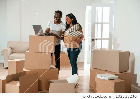 Wireless device, using laptop. African American couple are moving into new house Wireless device, using laptop. African American couple are moving into new house 132216236