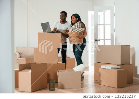 Wireless device, using laptop. African American couple are moving into new house Wireless device, using laptop. African American couple are moving into new house 132216237