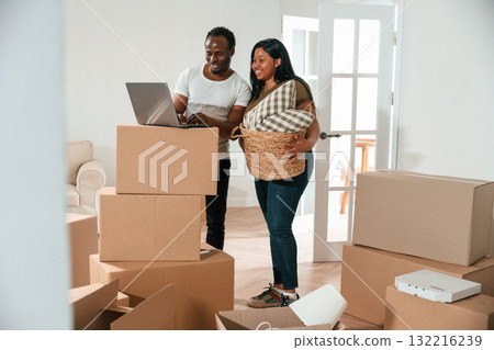 Wireless device, using laptop. African American couple are moving into new house Wireless device, using laptop. African American couple are moving into new house 132216239
