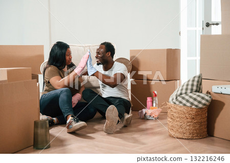 Tired of cleaning, sitting on the floor. African American couple are moving into new house 132216246