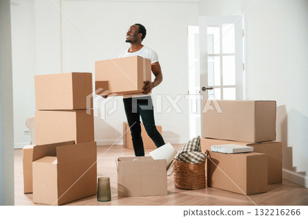 Happy black man is moving in his new home, holding box 132216266