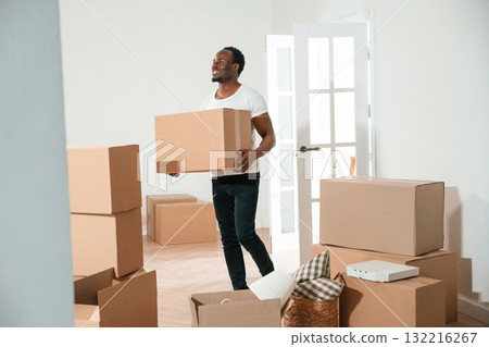 Happy black man is moving in his new home, holding box 132216267