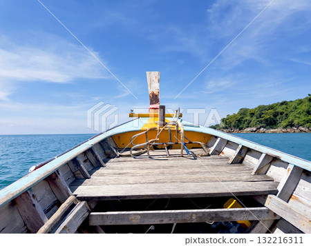 A view from a wooden longtail fishing boat sailing on the sea under a clear sky. Concept of travel and adventure. A view from a wooden longtail fishing boat sailing on the sea under a clear sky. Concept of travel and adventure. 132216311
