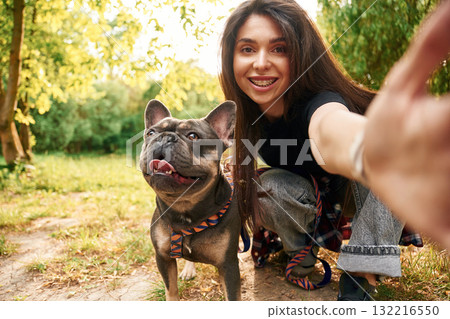 Smiling, making a selfie. Young pretty woman is with her dog in the park Smiling, making a selfie. Young pretty woman is with her dog in the park 132216550