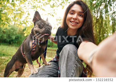 Making a selfie. Young pretty woman is with her dog in the park 132216552