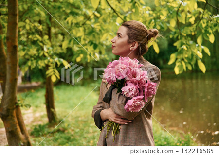Conception of gift of present. Beautiful young woman is with peonies flowers in the park 132216585