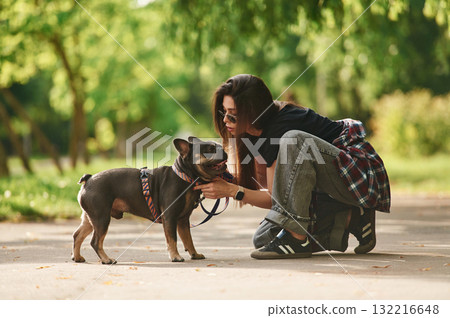 Side view, playing. Young pretty woman is with her dog in the park Side view, playing. Young pretty woman is with her dog in the park 132216648