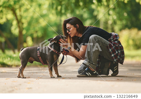 Side view, playing. Young pretty woman is with her dog in the park 132216649