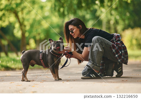 Side view, playing. Young pretty woman is with her dog in the park 132216650