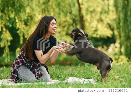 Side view, playing. Young pretty woman is with her dog in the park Side view, playing. Young pretty woman is with her dog in the park 132216651