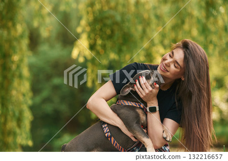 Embracing the animal. Young pretty woman is with her dog in the park 132216657