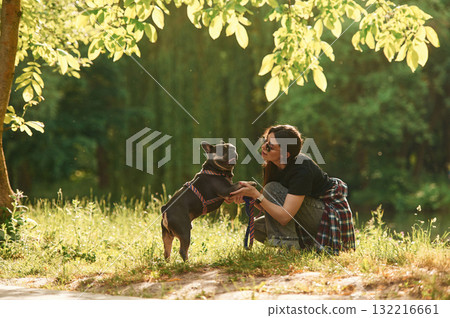 Under the bright sunlight. Young pretty woman is with her dog in the park 132216661