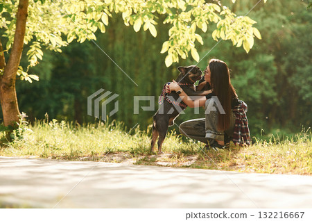 Under the bright sunlight. Young pretty woman is with her dog in the park Under the bright sunlight. Young pretty woman is with her dog in the park 132216667