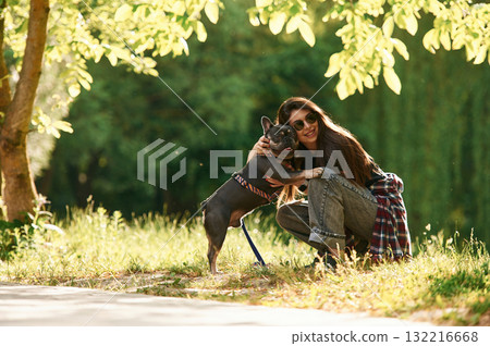 Under the bright sunlight. Young pretty woman is with her dog in the park Under the bright sunlight. Young pretty woman is with her dog in the park 132216668