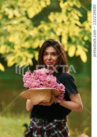 They are in the straw hat. Beautiful young woman is with pink flowers in the park They are in the straw hat. Beautiful young woman is with pink flowers in the park 132216680
