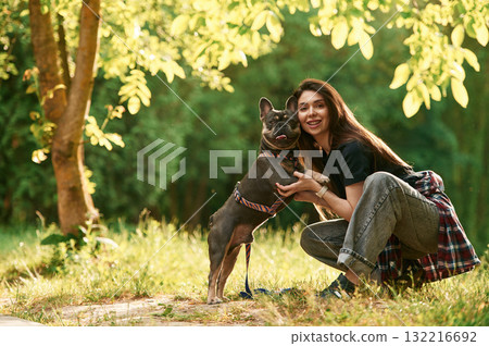 Sitting on the grass, embracing an animal. Young pretty woman is with her dog in the park Sitting on the grass, embracing an animal. Young pretty woman is with her dog in the park 132216692