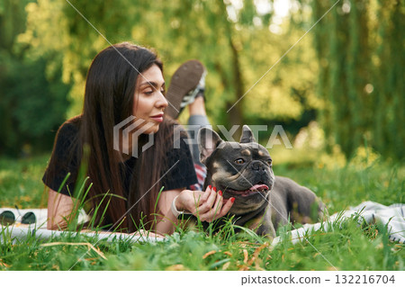 Beautiful female is outdoors. Young pretty woman is with her dog in the park Beautiful female is outdoors. Young pretty woman is with her dog in the park 132216704