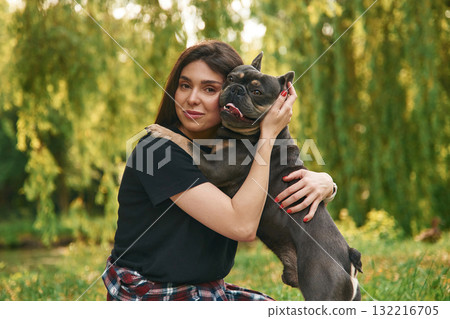 Beautiful female is outdoors. Young pretty woman is with her dog in the park Beautiful female is outdoors. Young pretty woman is with her dog in the park 132216705