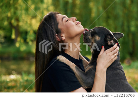Beautiful female is outdoors. Young pretty woman is with her dog in the park Beautiful female is outdoors. Young pretty woman is with her dog in the park 132216706