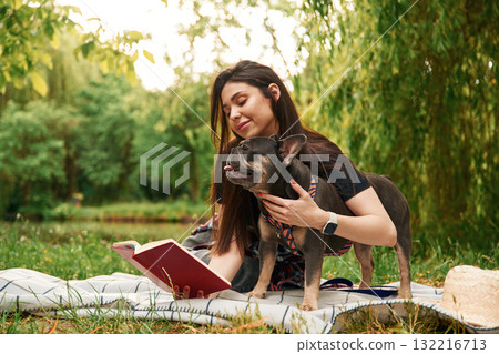 Red book, on the grass. Young pretty woman is with her dog in the park 132216713